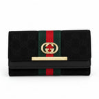 Gucci black wallet with GG Supreme canvas, green and red web stripe, gold-tone interlocking G logo, and a gold-tone GUCCI bar on a white background.
