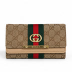 Gucci monogram canvas wallet in beige with a green and red web stripe, gold interlocking G logo, and a gold metal bar engraved with the brand name.