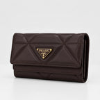 A dark brown Prada quilted leather wallet with a gold-tone triangular logo plaque on the front, set against a plain white background.