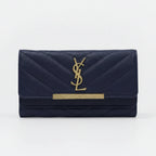 A navy blue quilted leather wallet with a gold-tone YSL monogram and a gold bar accent on the front, set against a plain white background.